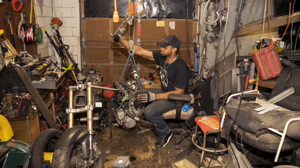 Prince Beatty continues to work on his motorcycle as he awaits for sheriff's deputies to start the eviction process at his home, Monday, Jan. 10, 2022, in East Point, Ga. Beatty, a 47-year-old Navy veteran, faces eviction this month for unpaid rent despite his landlord getting more than $20,000 in federal rental assistance. (AP Photo/Hakim Wright Sr.)