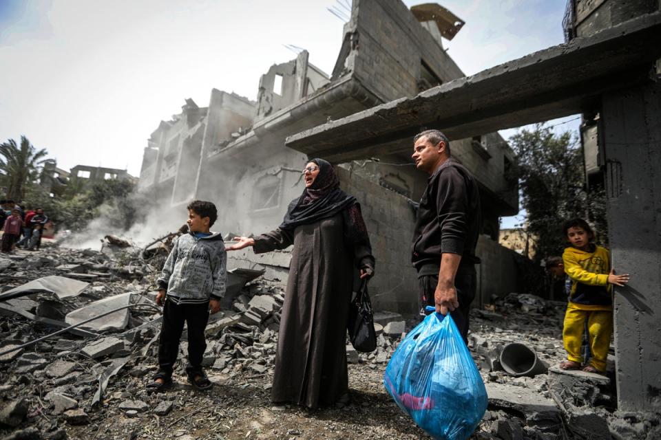 Palestinians collect their belongings from the rubble of a residential building after an Israeli airstrike in the Maghazi refugee camp in the Gaza Strip (AP)