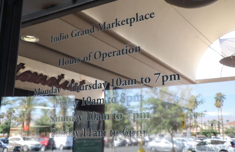 The hours of operation are posted on the window at the entrance to the Indio Grand Marketplace in Indio, Calif., March 24, 2022.