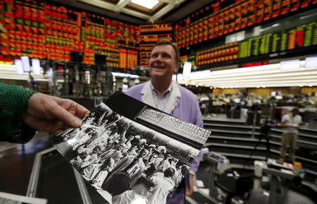 Thomas Cashman looks at some old family photos belonging to John Pietrzak (R) on the Chicago Board of Trade grain trading floor in Chicago, Illinois, United States, June 9, 2015. REUTERS/Jim Young