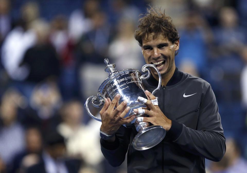 Rafael Nadal of Spain bites his trophy after defeating Novak Djokovic of Serbia in their men's final match at the U.S. Open tennis championships in New York, September 9, 2013.