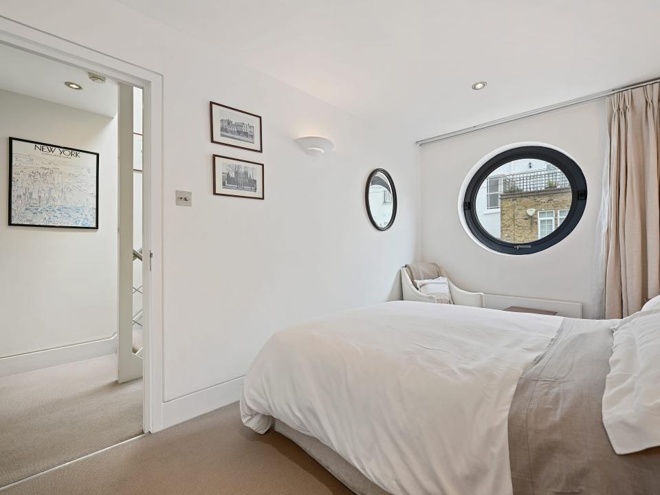 A white bedroom with a circular window