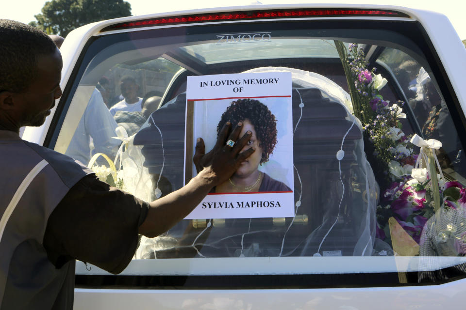 CAPTION CORRECTS SPELLING OF MAPHOSA A relative places his hand on a portrait of Sylvia Maphosa before her burial on the outskirts of the capital Harare, Saturday, Aug, 4, 2018.Maphosa was shot and killed by the Army during election related demonstrations in the capital Wednesday. Zimbabwean President elect Emmerson Mnangagwa won an election Friday with just over 50 percent of the ballots as the ruling party maintained control of the government in the first vote since the fall of longtime leader Robert Mugabe (AP Photo/Tsvangirayi Mukwazhi)