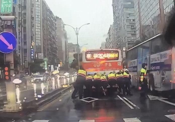 大雨滂沱公車拋錨，松山分局出動交通快打警力推車助脫困。（松山分局提供）