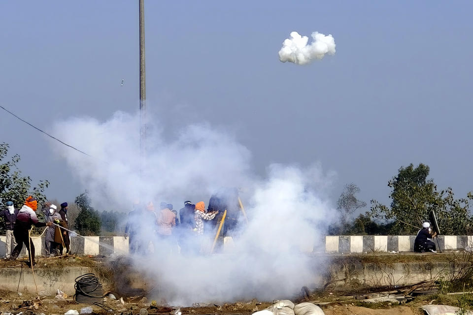 A farmer tries to douse a tear gas canister dropped by a police drone near Shambhu border that divides northern Punjab and Haryana states, almost 200 km (125 miles) from New Delhi, India, Wednesday, Feb.14, 2024. Protesting Indian farmers Wednesday clashed with police for a second consecutive day as tens of thousands of them tried to march to the capital New Delhi to demand guaranteed crop prices for their produce. (AP Photo/Rajesh Sachar)