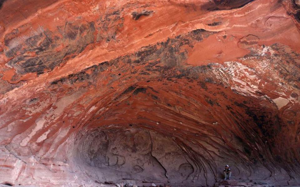 Tibetan youth sits at the base of a natural cave formation in Angsai, an area inside the Sanjiangyuan region in western China's Qinghai province on Sunday, Aug. 25, 2019.China has previously undertaken vast resettlement programs to clear land for large infrastructure projects, but in developing the national parks, the government is giving conservation-related jobs to at least a swath of people living in Sanjiangyuan to stay and work on their land. | Ng Han Guan/AP/Shutterstock