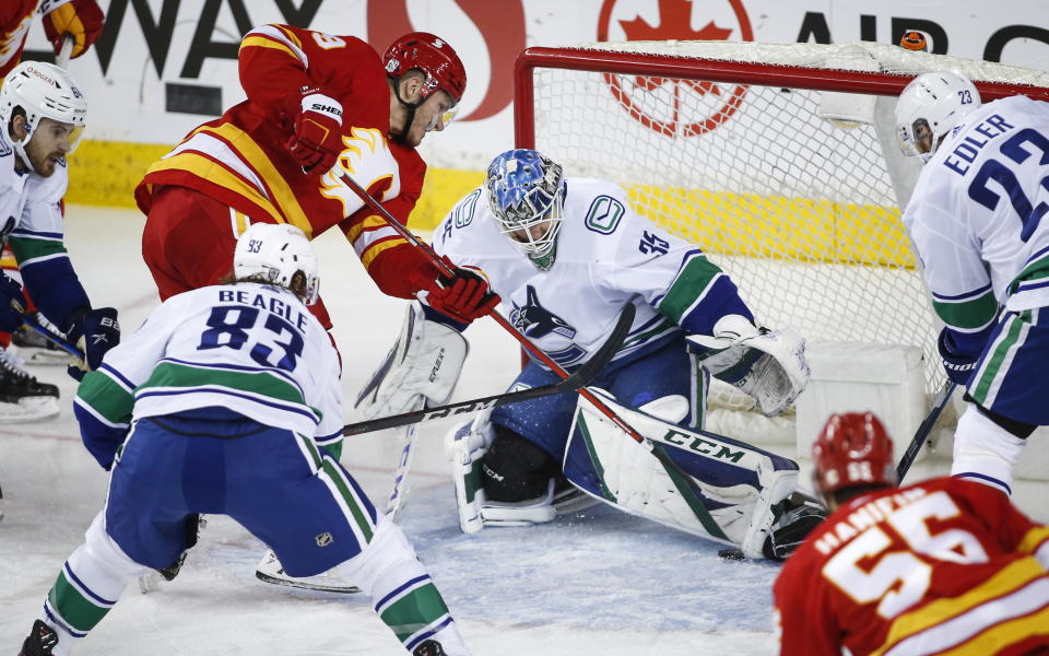 Vancouver Canucks goalie Thatcher Demko, right, gets his pad on a shot from Calgary Flames' Matthew Tkachuk during second-period NHL hockey game action in Calgary, Alberta, Monday, Jan. 18, 2021. (Jeff McIntosh/The Canadian Press via AP)