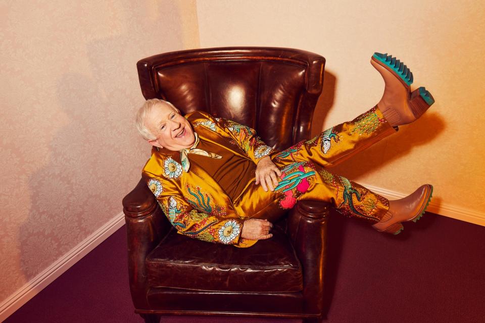 Leslie Jordan reclines in a chair in a western suit