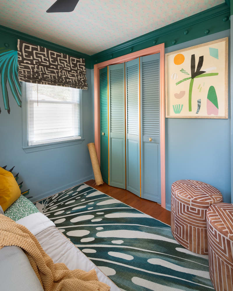 Coral painted trim on colorful closet in tropical themed bedroom.