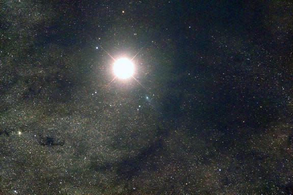 Comet Siding Spring (C/2013 A1) is seen near Mars (the bright object) as a bluish-green orb at the center in this view of the comet's extremely close flyby of the Red Planet on Oct. 19, 2014. This image was captured by astronomer Nick Howes and