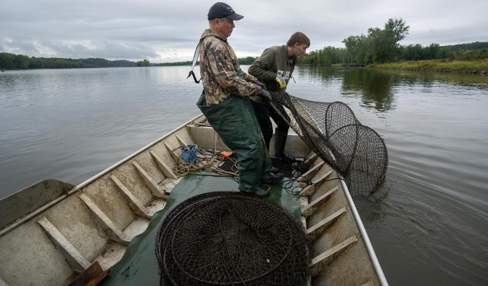Mike Valley, left, and his grandson, Bryce Priebe, haul in a net Sept. 26 on the Mississippi River near Cassville, Wisconsin. Valley is one of the last commercial fishermen on the upper Mississippi River, and has seen many changes to the river in the decades he's fished it.