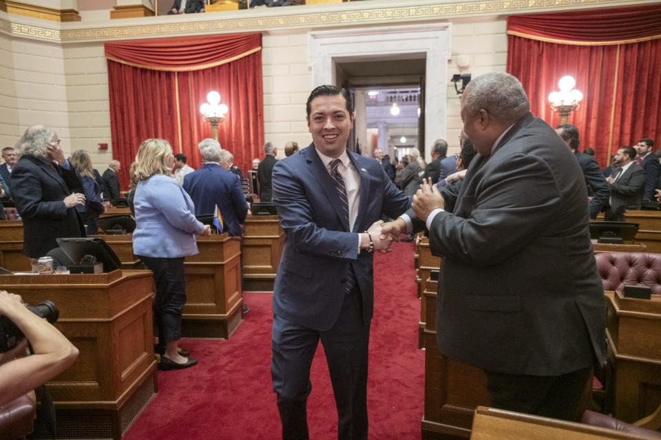 Daniel J. McKee, the 76th Governor of RI, gives his state of the state address in the House chamber. James J. Diossa, Treasurer, left, shaking hands with Rep. Ray Hull.<br> (Michael Salerno/Rhode Island Current)