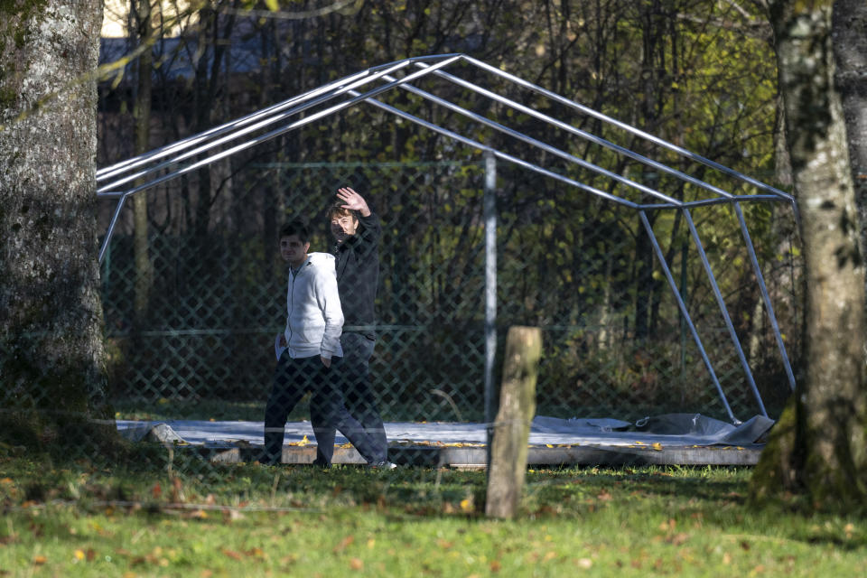 Two men walk in front of the framework of a tent that were set up as shelters for refugees in Sankt Georgen im Attergau, Austria, Monday, Nov. 14, 2022. In a weeks-long standoff with the Austrian government over the accommodation of rising numbers of asylum seekers in the alpine country, the mayor of the small village St. Georgen defied national housing measures and ordered the dismantling of more than a dozen tents for some 100 migrants in his community citing security concerns. (AP Photo/Andreas Schaad)