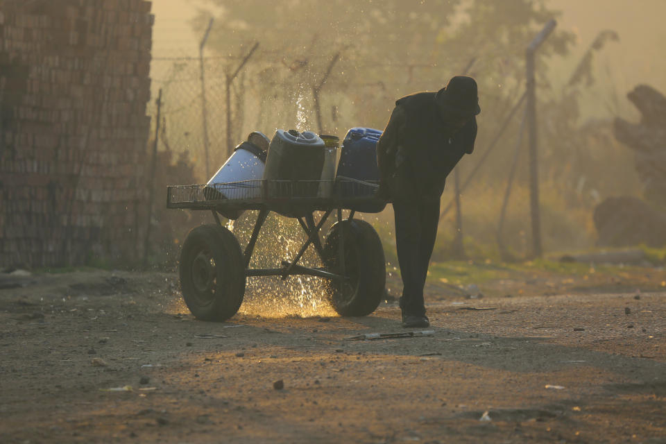 A man pushes a cart with buckets filled with water in Harare, Friday , Aug 9, 2019. Fuel prices and the cost of living continue to rise in Zimbabwe due to the volatility of the recently introduced new currency, as the population struggles with water and power shortages. (AP Photo/Tsvangirayi Mukwazhi)