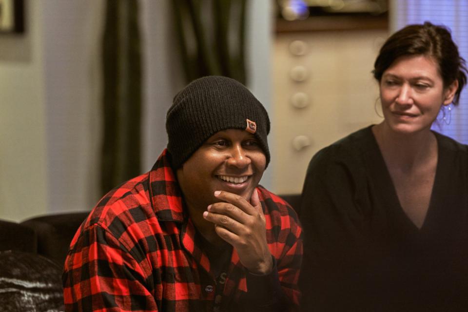 A man with his chin in his hand and a woman sit side by side on a couch