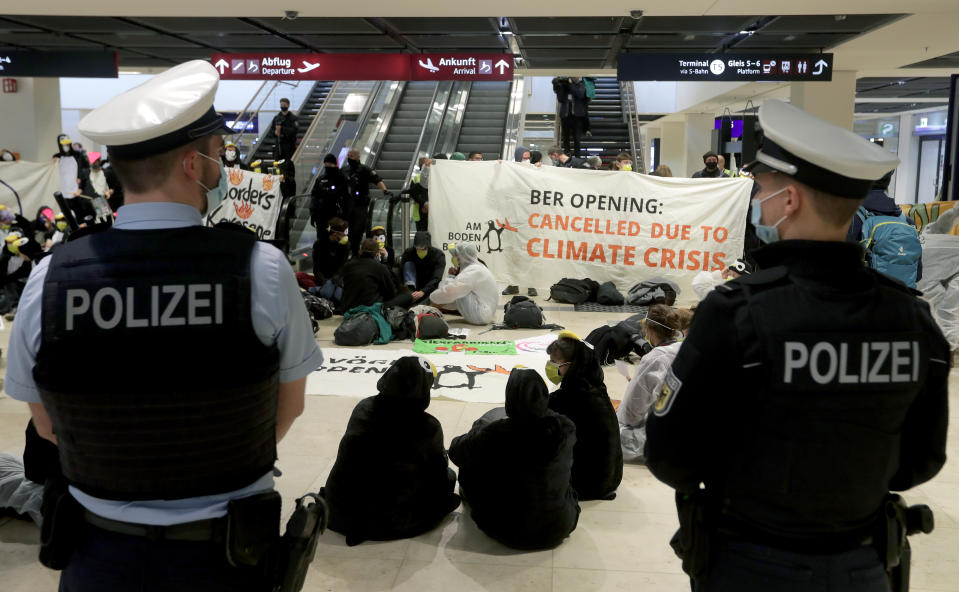 Activists block an escalator to protest against the opening of the new Berlin-Brandenburg-Airport 'Willy Brandt' in Berlin, Germany, Saturday, Oct. 31, 2020. Berlin's new airport opens after years of delays and cost overruns. (AP Photo/Michael Sohn)