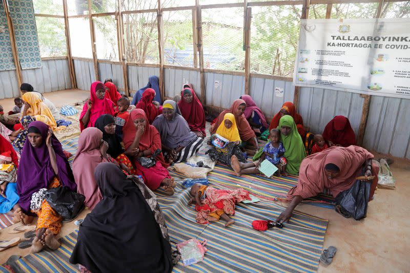Internally displaced Somali women sit with their children as they wait for malnutrition screening at the Dollow hospital, in Dollow