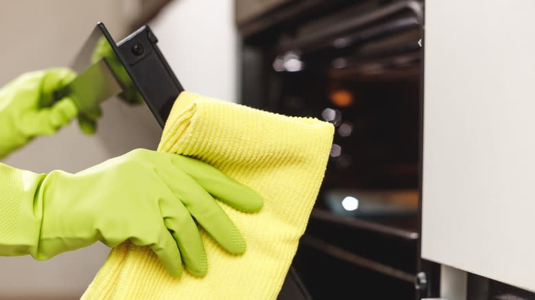 Gloved hands cleaning oven door
