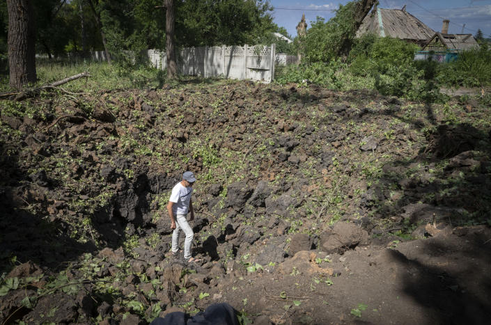 A man inspects the crater left by the Russian rocket in Bakhmut, Donetsk region, Ukraine, Friday, June 24, 2022..(AP Photo/Efrem Lukatsky)