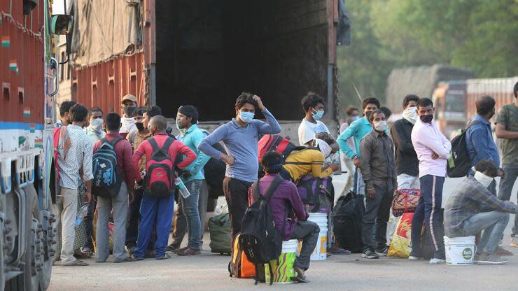 In der Stadt Hyderabad warten Wanderarbeiter mit Schutzmasken auf einen Transport in ihre Heimatorte. Nun soll ein Konjunkturprogramm die Wirtschaft des Landes stützen. Foto: dpa