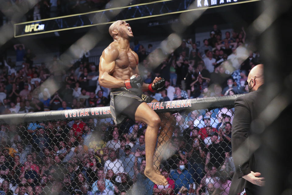 Kamaru Usman celebrates his win atop the octagon fence after a UFC 261 mixed martial arts bout against Jorge Masvidal early Sunday, April 25, 2021, in Jacksonville, Fla. (AP Photo/Gary McCullough)