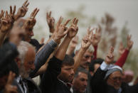 FILE - In this Oct. 11, 2014 file photo, mourners flash the victory sign as they sing a nationalistic Kurdish song at a cemetery in Suruc, Turkey during the funeral of two Syrian Kurdish fighters, who were killed in fighting with militants of the Islamic State group in Kobani, Syria. Syria’s Kurds have been America’s partner in fighting the Islamic State group for nearly four years. Now they are furious over an abrupt U.S. troop pull-back that exposes them to a threatened attack by their nemesis, Turkey. The surprise U.S. pull-back from positions near the Turkish border, which began Monday, Oct. 7, 2019, stung even more because the Kurds have been abandoned before by the U.S. and other international allies on whose support they'd pinned their aspirations. (AP Photo/Lefteris Pitarakis, File)