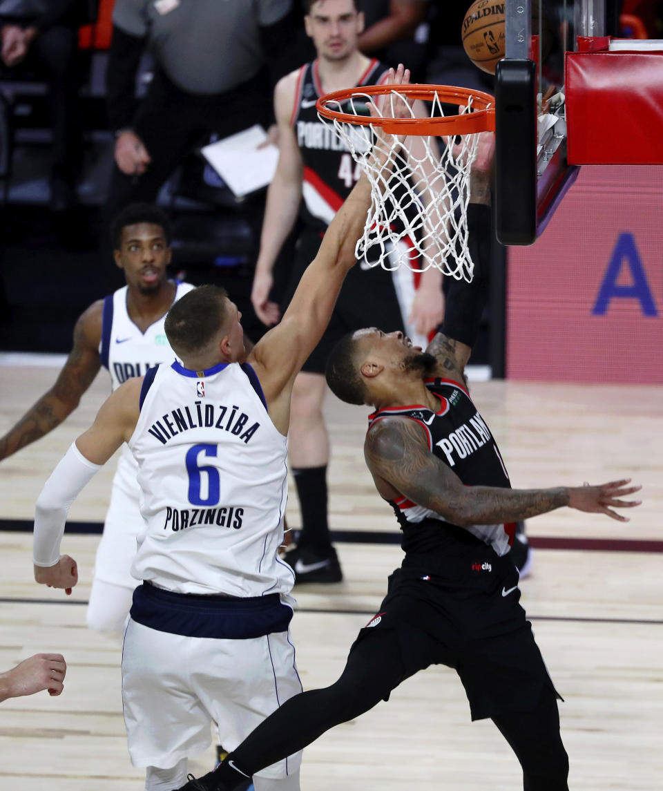 Portland Trail Blazers guard Damian Lillard (0) shoots as Dallas Mavericks forward Kristaps Porzingis (6) defends during the second half of an NBA basketball game Tuesday, Aug. 11, 2020, in Lake Buena Vista, Fla. (Kim Klement/Pool Photo via AP)