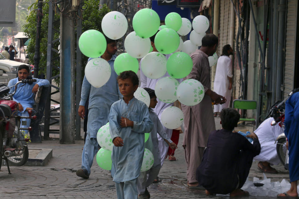 A vendor holds balloons of National flag color with letters reading ''happy Independence Day'' at a market in Peshawar, Pakistan, Monday, Aug. 14, 2023. Millions of Pakistanis celebrate the 76th Independence Day from British rule. (AP Photo/Muhammad Sajjad)