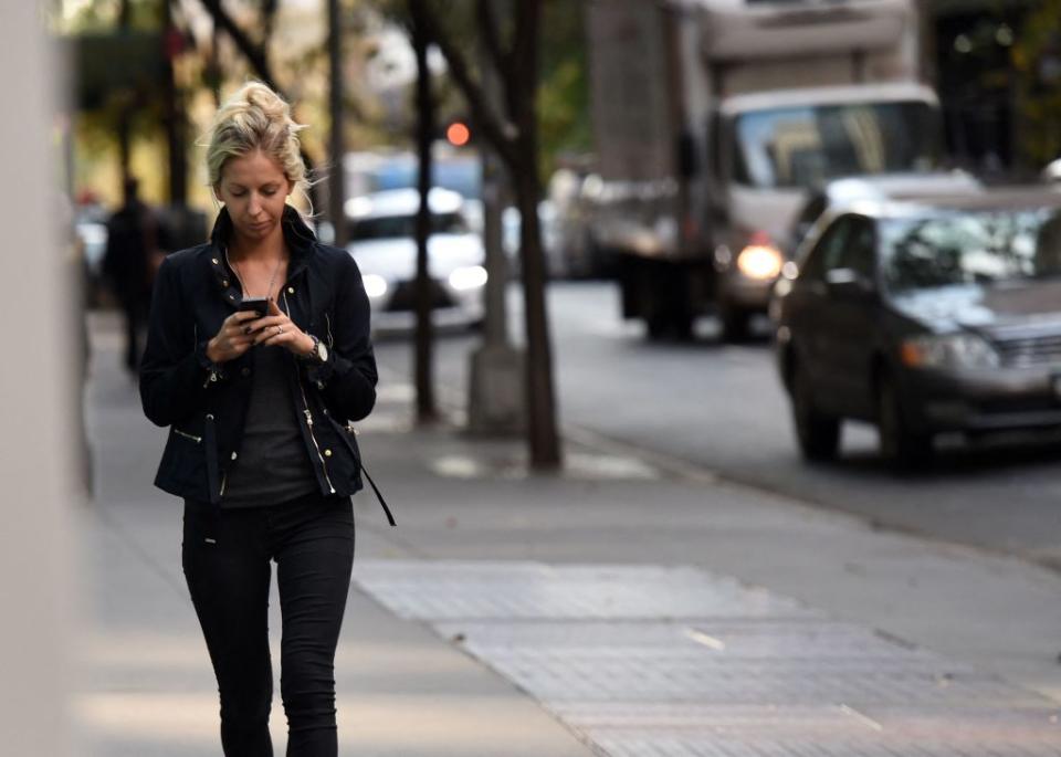 A woman walks with her phone on 47th Street in Manhattan, which is the borough with the worst service, according to a new survey. AFP via Getty Images