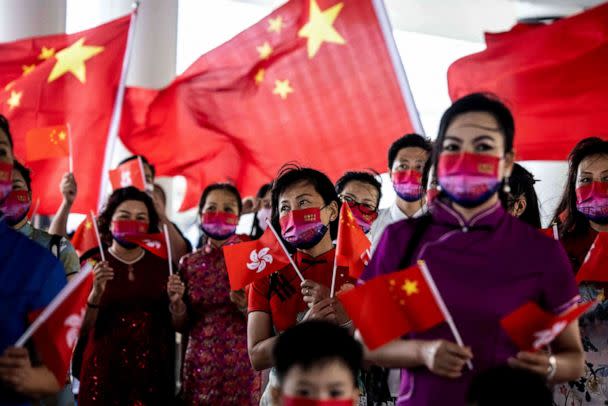 PHOTO: People hold the Hong Kong and Chinese flags while singing to celebrate the 25th anniversary of the city's handover from Britain to China, in Hong Kong on July 1, 2022. (Isaac Lawrence/AFP via Getty Images)