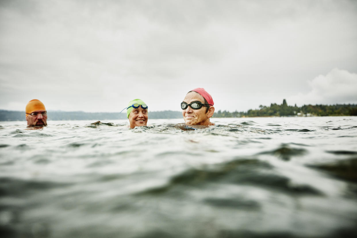 Smiling group of mature swimmers resting during open water swim