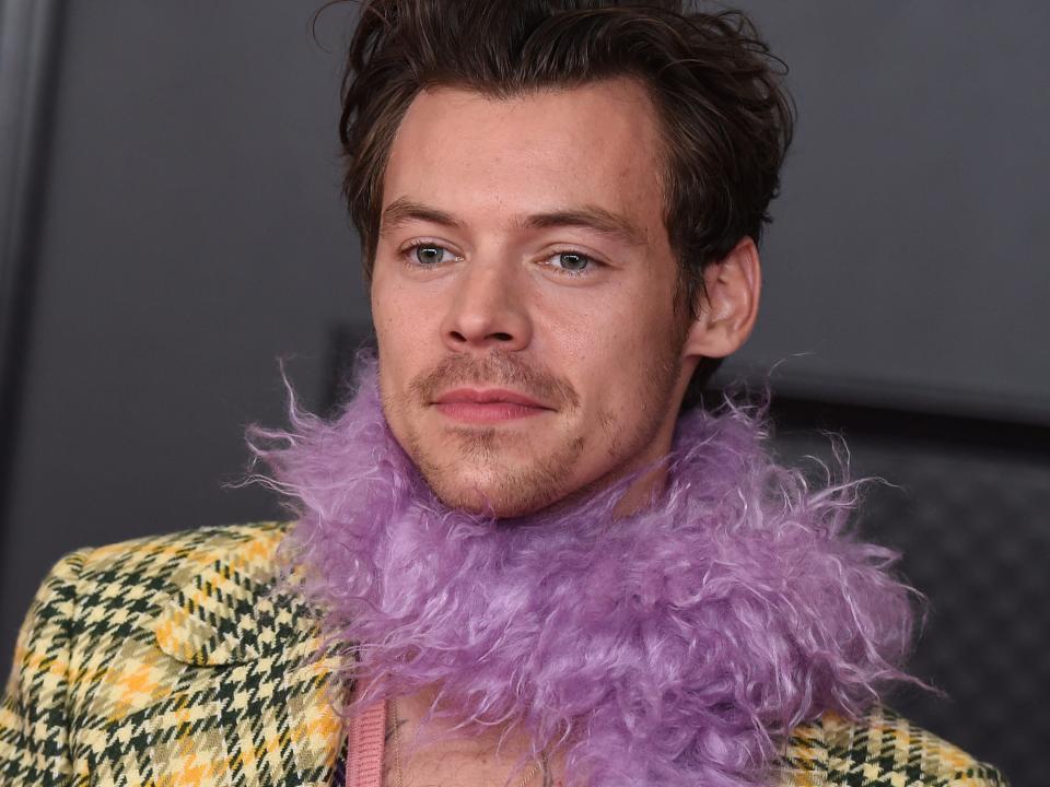 Harry Styles wears a plaid jacket and purple feather boa at the 2021 Grammys.