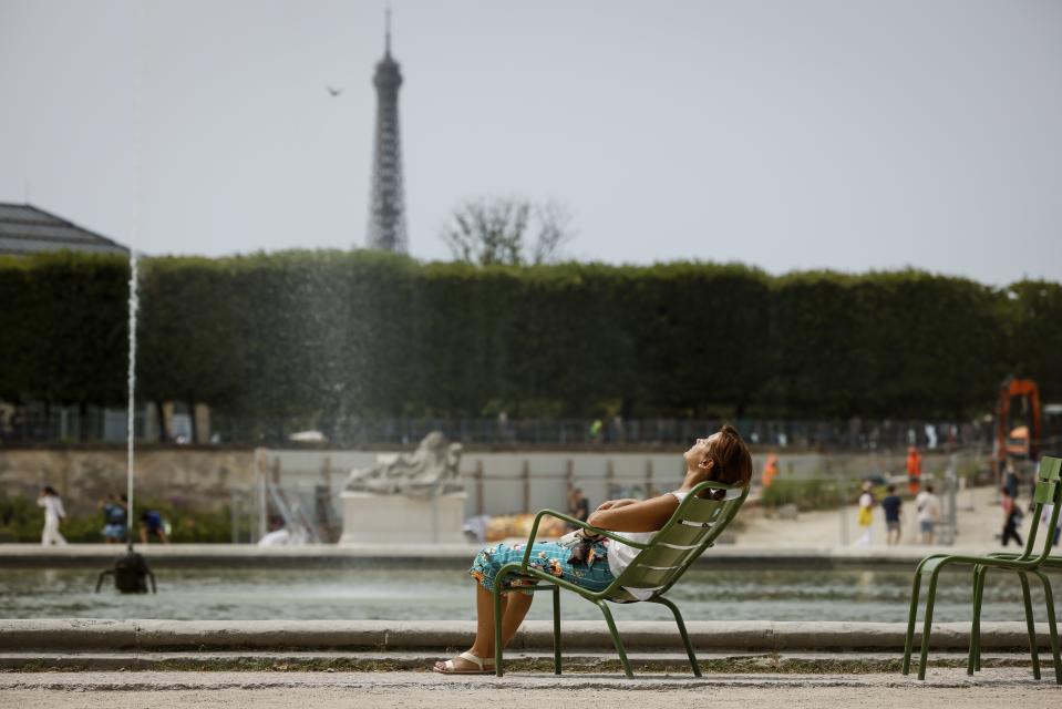 FILE - A woman enjoys the sun in the Tuileries gardens, Monday, July 10, 2023, in Paris where temperatures are expected to rise. The use of Paris monuments as outdoor venues for competition will be televisual. But they could also be insufferably hot if France is baking through another of its worsening heat waves. (AP Photo/Thomas Padilla, File)