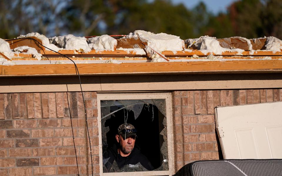 A man looks out of a broken window from a home that was destroyed by a tornado in Powderly, Texas, Saturday, Nov. 5, 2022.