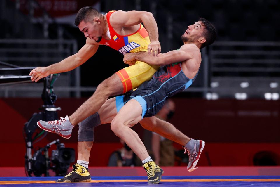 <p>Iran's Mohammadreza Geraei (blue) wrestles Colombia's Julian Stiven Horta Acevedo in their men's greco-roman 67kg wrestling early round match during the Tokyo 2020 Olympic Games at the Makuhari Messe in Tokyo on August 3, 2021. (Photo by Jack GUEZ / AFP)</p> 