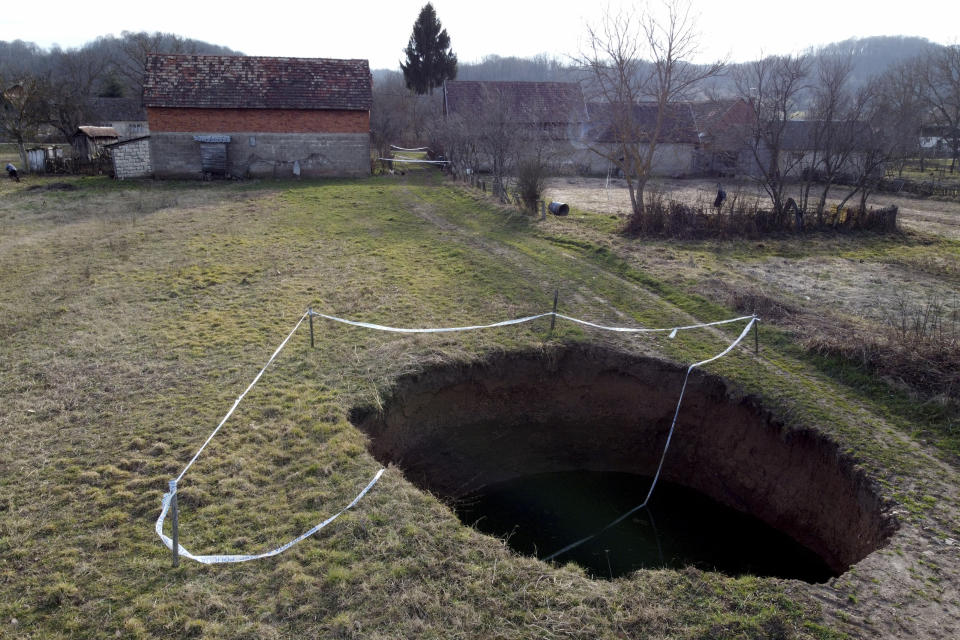 This aerial photo shows a sinkhole in the village of Mececani, central Croatia, Thursday, March 4, 2021. A central Croatian region about 40 kilometers (25 miles) southwest of the capital Zagreb is pocked with round holes of all sizes, which appeared after December's 6.4-magnitude quake that killed seven people and caused widespread destruction. Scientists have been flocking to Mecencani and other villages in the sparsely-inhabited region for observation and study. (AP Photo/Darko Bandic)