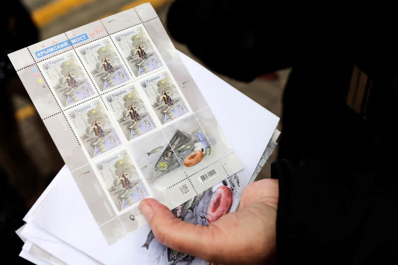 A woman holds new commemorative Crimea bridge destruction anti-Russian stamps at a post office in Kyiv