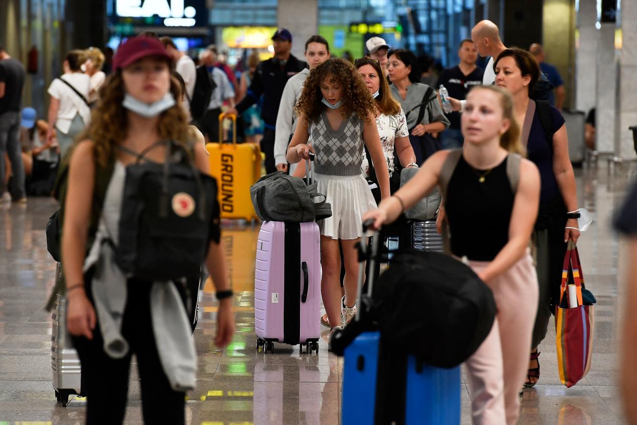 Travelers push their luggages at the Terminal 2 of El Prat airport in Barcelona on July 12, 2022. (Photo by Pau BARRENA / AFP)
