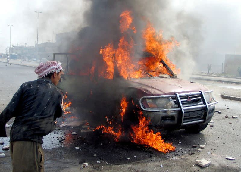 FILE PHOTO: FILE PHOTO: Iraqi man looks at blazing vehicle after attack in Falluja