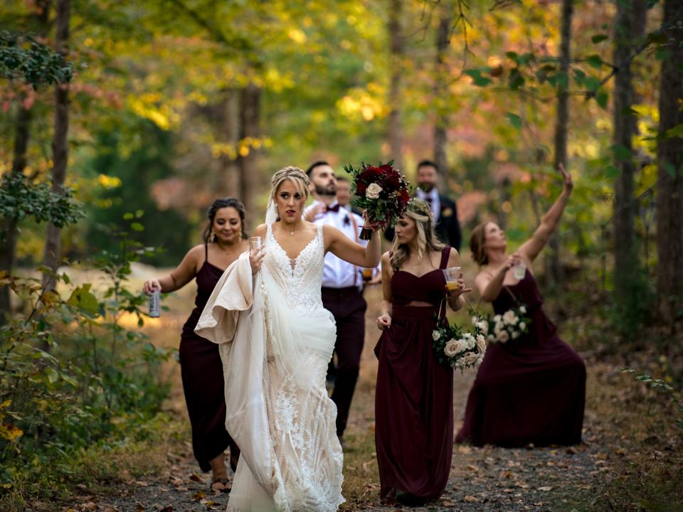 The bride and bridesmaids walking through a trail in the forest during campground wedding