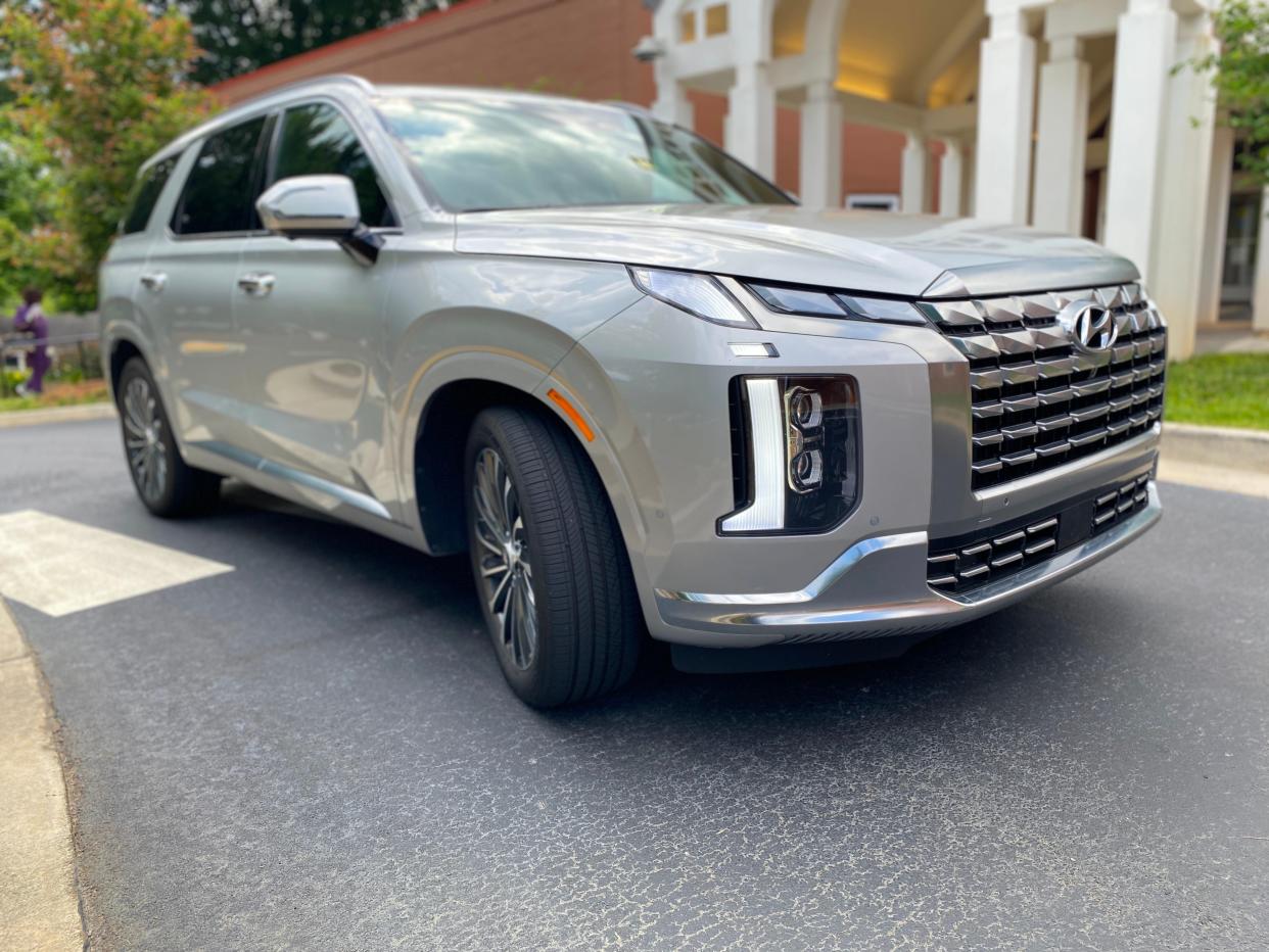 A silver Hyundai Palisade Calligraphy parked in front of a building