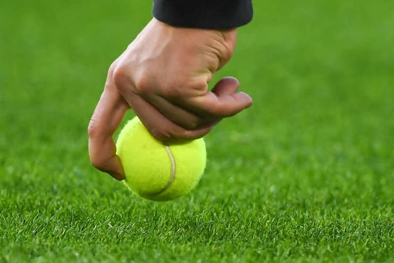 A helper collects a tennis ball thrown onto the pitch during the German Bundesliga soccer match between VfL Wolfsburg and Borussia Dortmund at the Volkswagen Arena. Swen Pförtner/dpa