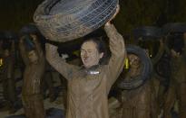 A trainee holds up a tyre during the Tianjiao Special Guard/Security Consultant Ltd. bodyguard training camp in Beijing, November 1, 2013. Trainees include former soldiers, college graduates and retired athletes. About 65 people took part in the intensive training camp teaching Israeli martial arts, driving, shooting and business etiquette. Picture taken November 1, 2013. REUTERS/Stringer (CHINA - Tags: SOCIETY EDUCATION) CHINA OUT. NO COMMERCIAL OR EDITORIAL SALES IN CHINA