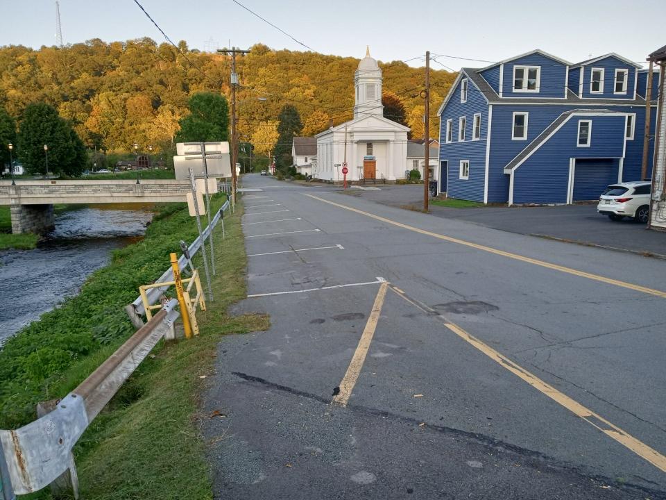 Twelfth Street, Honesdale, looking from the corner of the bridge at Main Street, shows the section in the foreground between Main and Church streets slated for pedestrian and green space improvements, which are to continue all the way down to the former Industrial Point where the County of Wayne is planning to create Sycamore Point, a riverside park with an improved river boating access and parking. In view is the Honesdale Community Church, and Irving Cliff in the distance.