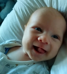 A baby boy smiling at camera.