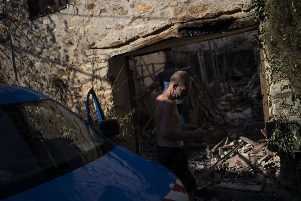 A resident inspects damage caused by wildfires in Val de Gilly, southern France, Thursday, Aug. 19, 2021. A fire that has ravaged forests near the French Riviera for four days is slowing down as winds and hot weather subside, but more than 1,100 firefighters were still struggling to get it under control Thursday, local authorities said. (AP Photo/Daniel Cole)