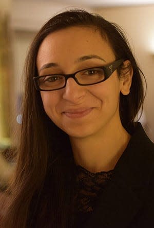 A young woman with glasses looks at the camera.