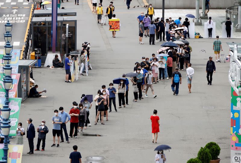 People wait in line for a coronavirus disease (COVID-19) test at a testing site which is temporarily set up at a railway station in Seoul