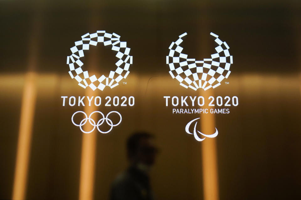 FILE - In this June 11, 2019, file photo, a man walks past the logos of the Tokyo 2020 Olympics and Paralympics in Tokyo. The Japanese government and Tokyo 2020 organizers are hoping to use the Olympics to showcase Japan's recovery from the 2011 earthquake and tsunami. But with less than a year to go before the opening ceremony, Rifu Mayaor Yutaka Kumagai in Miyagi prefecture, northern Japan, said Saturday, Sept. 14, 2019, his city has seen no benefit from the Olympics. He criticized the central government over its failure to use the 2020 Tokyo Olympics to help in the reconstruction of the region. (AP Photo/Jae C. Hong, File)