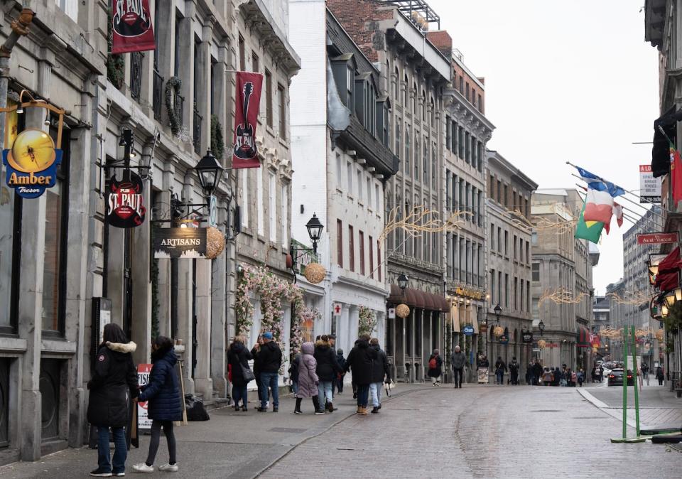 An unusually mild start to winter in Quebec is dampening spirits in a province otherwise known for its vibrant winter culture. People walk on the snowless streets in Old Montreal. (Ryan Remiorz/The Canadian Press - image credit)